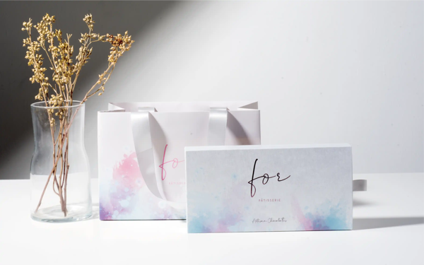 A mockup of a drawer style rigid box with drawers and a ribbon paper bag on a gray background
