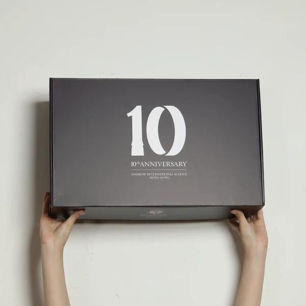 Hands showing a mockup of a colorful mailing box with "10" printed on it, on a gray background
