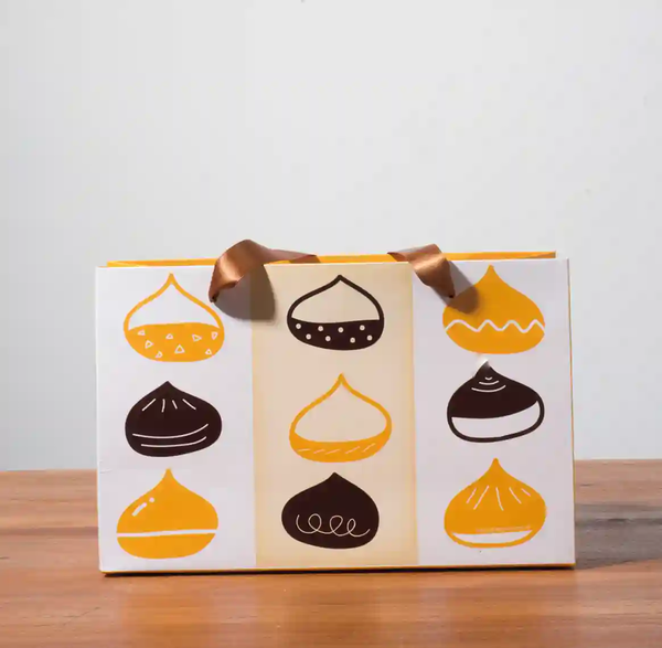 A mockup of a ribbon paper bag displayed on a gray background and wood grain tabletop